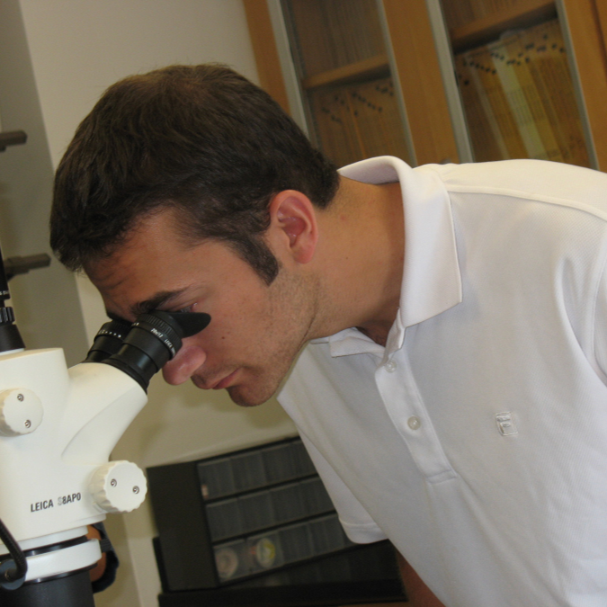 A young man looking into a microscope.