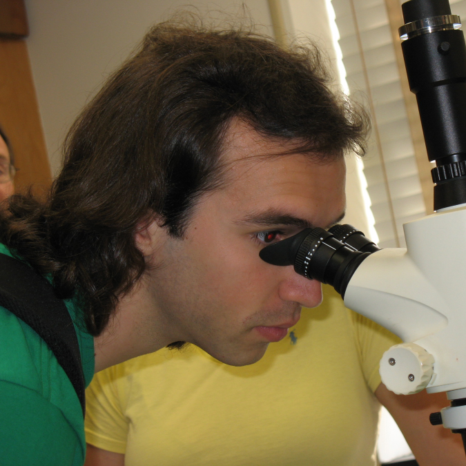 A young man looking into a microscope.